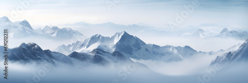a panoramic view of snowy mountains with snow covered peaks covered with fog and snow in winters photo