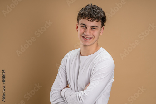Portrait of one caucasian man 20 years old looking to the camera in front of almond color studio background smiling wearing casual shirt copy space © Miljan Živković