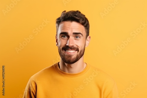 Portrait of a smiling young man looking at camera over yellow background © Inigo