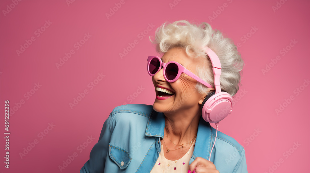 Crazy cool granny, elderly woman with headphones, sunglasses and gray hair, expressive mature and happy smiling grandmother in colorful close-up portrait - obrazy, fototapety, plakaty 