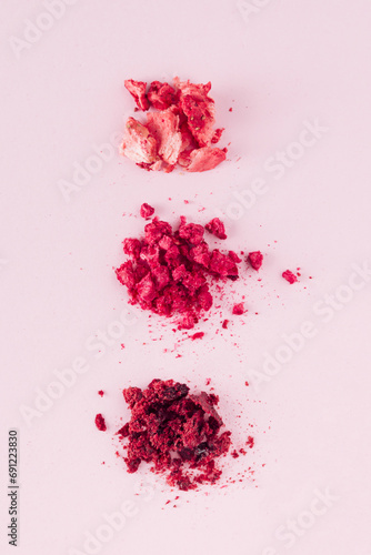 Smashed dehydrated fruits on the pastel pink background. Flat lay photography of dried strawberries, raspberries, and cherries. Natural healthy snack