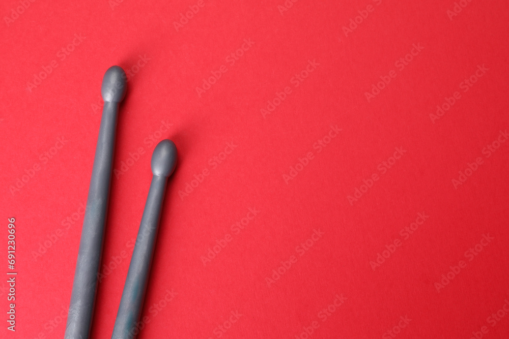 Two gray drum sticks on red background, top view. Space for text Two gray drum sticks on red background, top view. Space for text