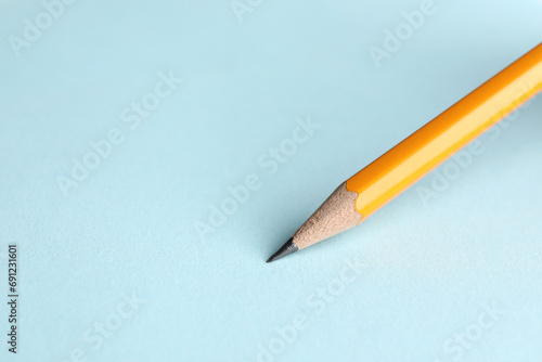 Drawing with sharp graphite pencil on light blue background, closeup. Space for text