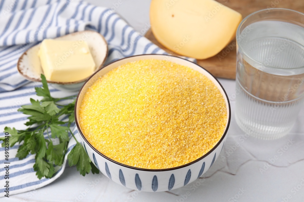 Raw cornmeal in bowl, water, cheese, parsley and butter on light table, closeup Raw cornmeal in bowl, water, cheese, parsley and butter on light table, closeup