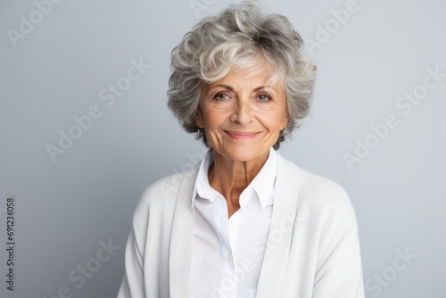 Portrait of a happy senior woman looking at camera against grey background