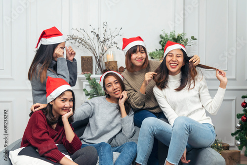 Christmas party Group of Asian Woman talk, play game, party, exchange christmas gift box under xmas tree. Young women enjoy laughing sitting together living room celebrate christmas holiday festival