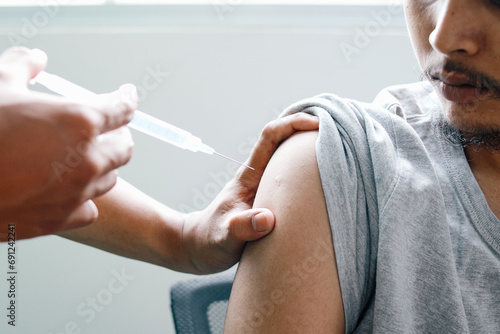 Doctor injecting male patient with syringe in the clinic photo