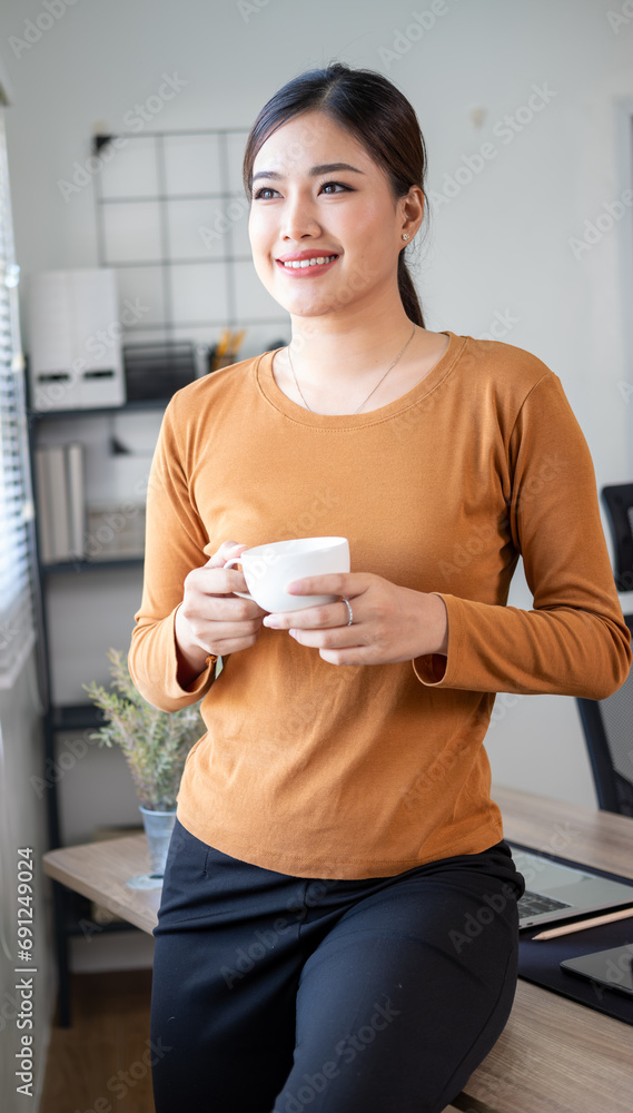 Successful businesswoman smiling holding coffee cup at office. Confident business woman sitting drinking coffee in the office. Successful businesswoman smiling holding coffee cup at office. Confident business woman sitting drinking coffee in the office.