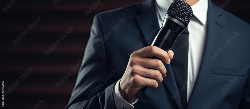 Young male economist presenting to colleagues in formal attire with a microphone. Young male economist presenting to colleagues in formal attire with a microphone.