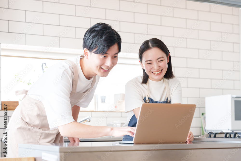 Obraz premium キッチンでパソコンを見て話す男女