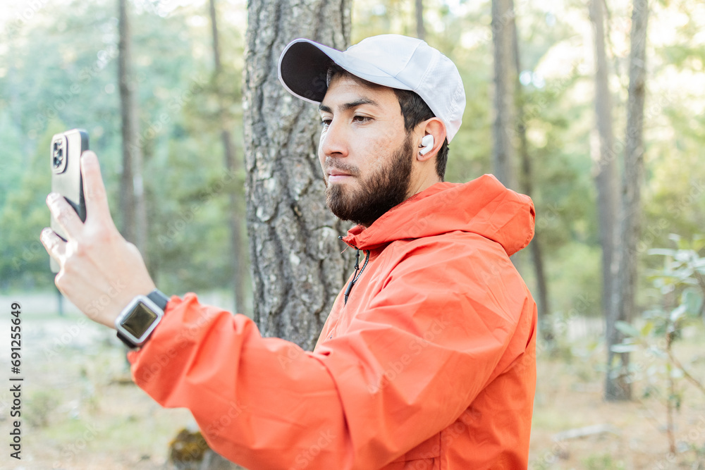 Hombre joven con barba tomando una selfie en el bosque. Hombre joven con barba tomando una selfie en el bosque.