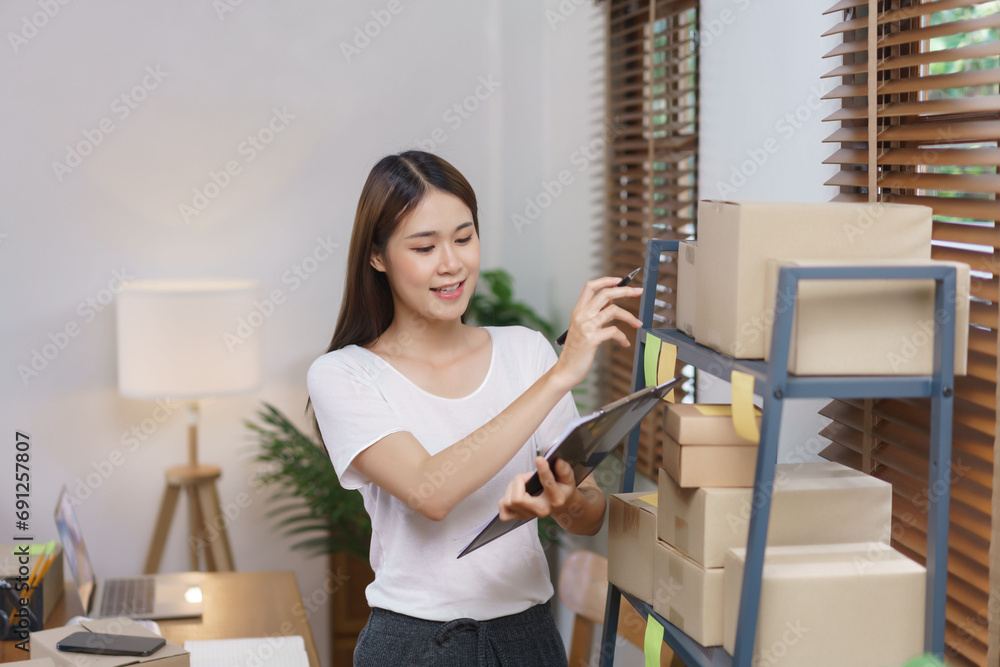 Online selling concept, Asian business women holding clipboard to checking products in store Online selling concept, Asian business women holding clipboard to checking products in store