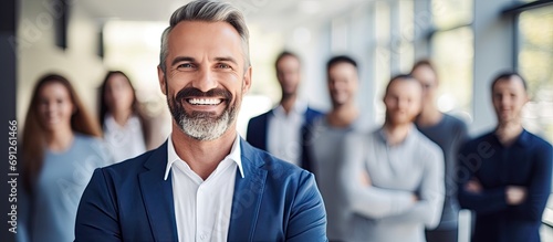 Happy white male boss smiling with crossed hands during daytime for collaborative brainstorming with engaged employees in association synergy, enjoying crew teamwork. photo
