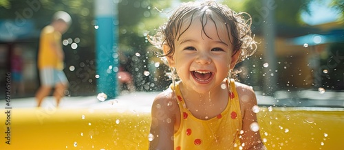 Funny Caucasian girl playing on splash pad playground, a summer water activity for kids outdoor. photo