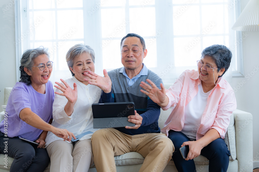 Happiness of the group females and male elderly talking with Video Call from smart tablet. Senior people are talking and enjoy together at the living room. Joyful retired friends enjoying relaxation. Happiness of the group females and male elderly talking with Video Call from smart tablet. Senior people are talking and enjoy together at the living room. Joyful retired friends enjoying relaxation.