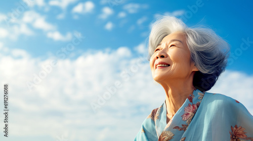 Happy Elderly Japanese Woman with Gray Hair Looks Into The Blue Sky