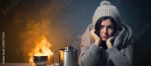 Woman with hot drink and bill trying to keep warm by radiator during energy crisis photo