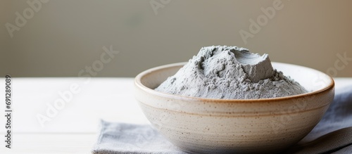 Close-up of gray bentonite clay in a small white bowl--DIY mask, body wrap recipe. Natural spa treatment, top view, copy space. photo