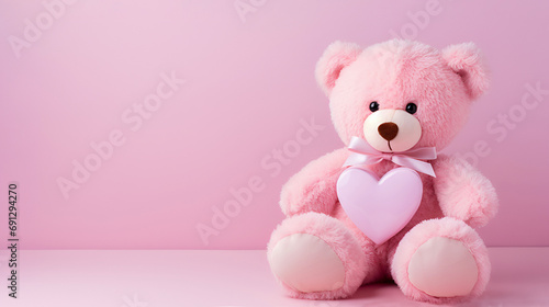 Pink teddy bear with a pink heart on a pink background with copy space. © Наталья Зюбр