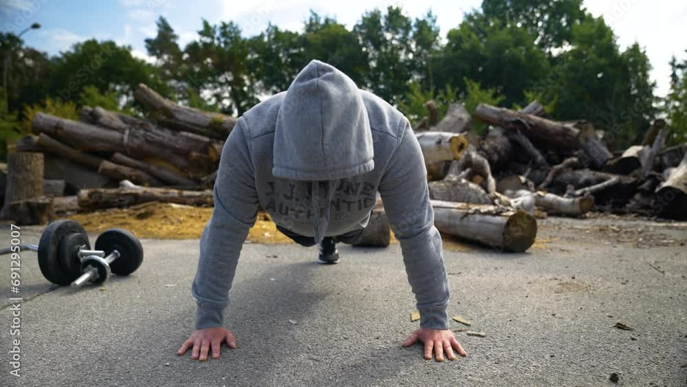 Motivated Man In Hoodie Jacket Doing Push Ups On The Ground Outdoor. closeup Motivated Man In Hoodie Jacket Doing Push Ups On The Ground Outdoor. closeup