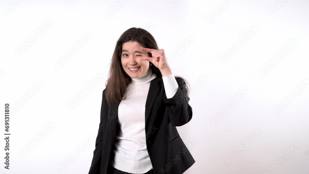 Smartly dressed smiling young brunette against white background using her forefinger and big finger to show that something is tiny and laughing afterwards Smartly dressed smiling young brunette against white background using her forefinger and big finger to show that something is tiny and laughing afterwards