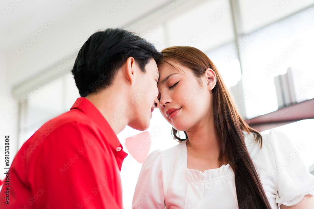 Young Asian romantic happy couple touching foreheads, closing their eyes with smiling enjoying the tender romantic moment and sharing affectionate feelings in living room. Valentine's Day celebration Young Asian romantic happy couple touching foreheads, closing their eyes with smiling enjoying the tender romantic moment and sharing affectionate feelings in living room. Valentine's Day celebration