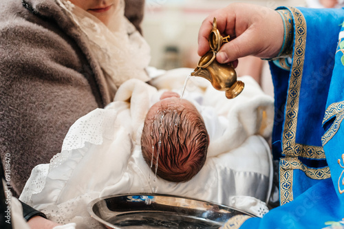 Canvas Print A priest pours water on the head of a small child during a Christian rite of baptism in a church