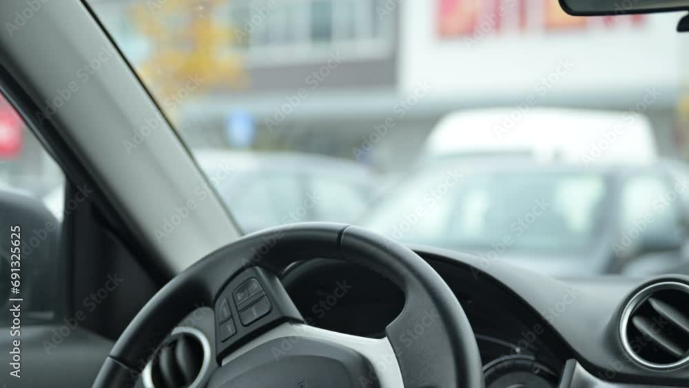 Car steering wheel and dashboard, vehicle on parking lot of large shopping mall in winter Car steering wheel and dashboard, vehicle on parking lot of large shopping mall in winter
