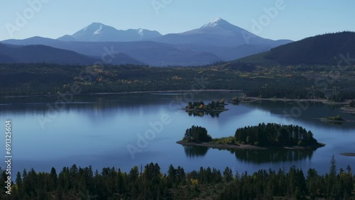 Early fall colors Lake Dillon islands Colorado aerial cinematic drone morning view Frisco Breckenridge Silverthorne Ten Mile Range calm reflective water yellow Aspen trees to the right movement photo