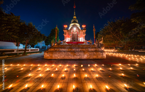 candles ligt around it in a temple. Candles burning around in area of front of chapel or church. Light of Lanna Candle Trays in loy krathong night. Yi peng festival Chiang Mai Thailand.. photo