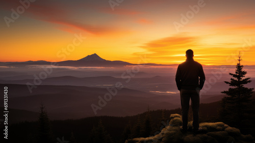 A person standing on a mountain top  looking out at a beautiful sunset