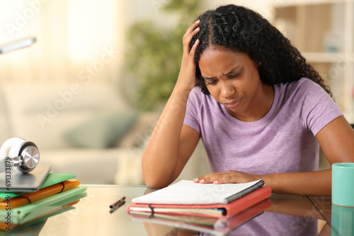 Worried black student memorizing notes at home