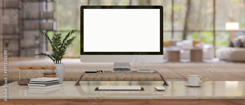 A computer mockup on a computer stand with accessories on a table in a modern spacious living room.