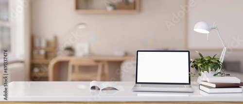 Close-up image of a white-screen laptop computer on a white tabletop in a modern Scandinavian room. © bongkarn