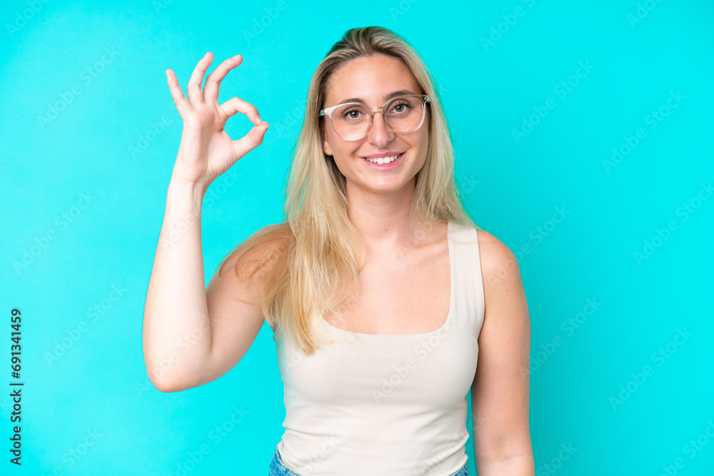 Fototapeta premium Young caucasian woman isolated on blue background With glasses and doing OK sign