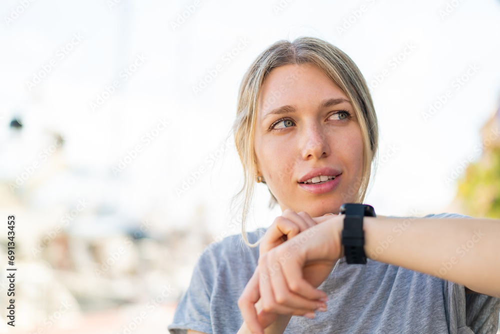Young blonde woman at outdoors with sport watch