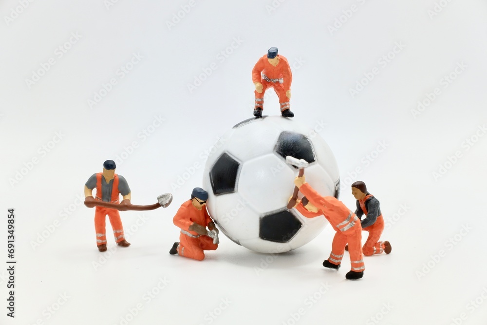 miniature figurines of a men at work team working on a soccer balloon