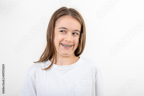 Funny teenage girl in braces laughs on a white background.