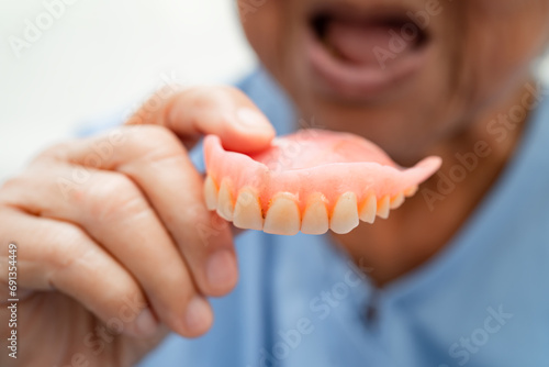 Asian elderly woman patient holding to use denture, healthy strong medical concept. photo