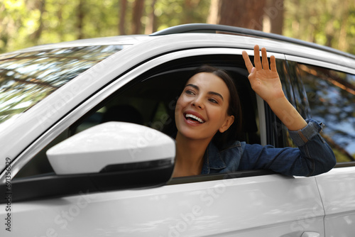 Happy young woman looking out of car window, view from outside. Enjoying trip