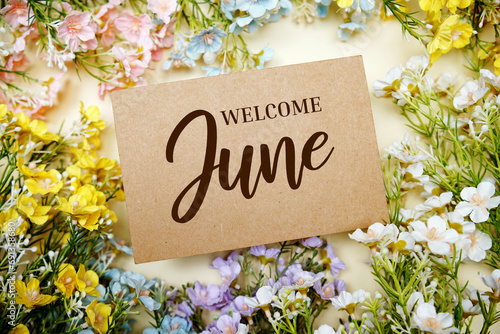 Welcome June text message with flower decoration on yellow background photo