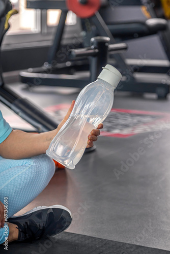 Woman with a bottle of water in the gym after a workout.