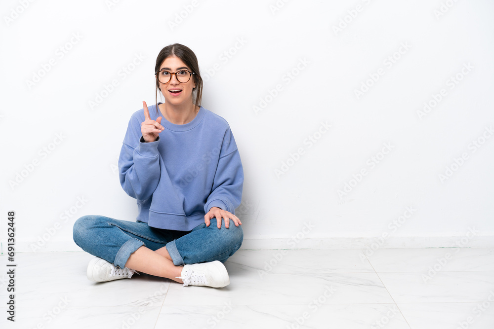 Young caucasian woman sitting on the floor isolated on white background thinking an idea pointing the finger up Young caucasian woman sitting on the floor isolated on white background thinking an idea pointing the finger up