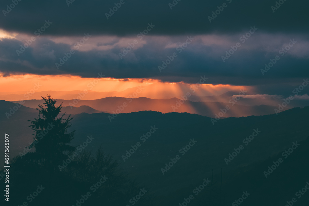 Sunset with rays of light falling from the sky. Stunning alpine landscape with golden skies and dramatic clouds