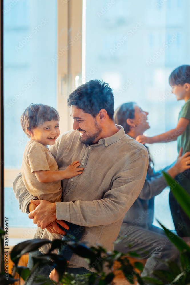 Father carrying son in arms with family at home Father carrying son in arms with family at home