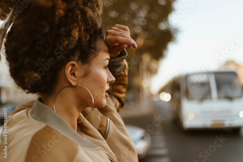 Young woman touching forehead at street photo