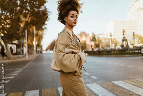 Fashionable woman crossing street in city photo