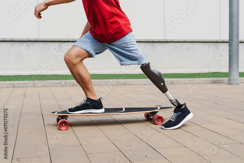 Man with prosthetic leg riding skateboard at footpath photo