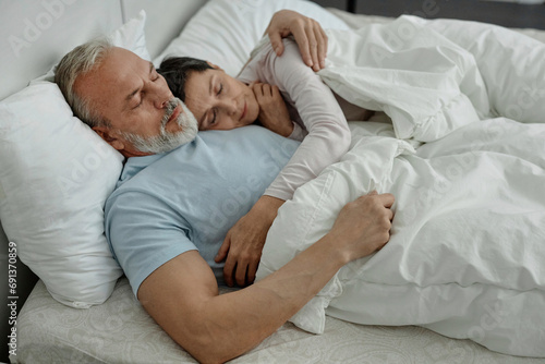 Couple cuddling each other during sleep in bed photo