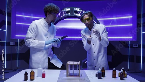 Portrait of caucasian biochemists in white uniform performing clinical trials. Male scientists developing new medical drug in the laboratory. High quality 4k footage photo